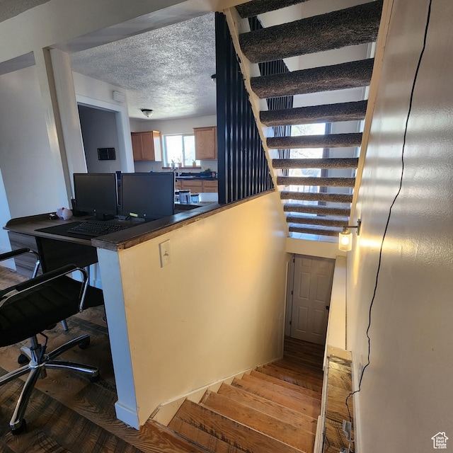 staircase with a textured ceiling and wood finished floors