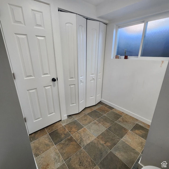 unfurnished bedroom with a closet, baseboards, and stone finish floor