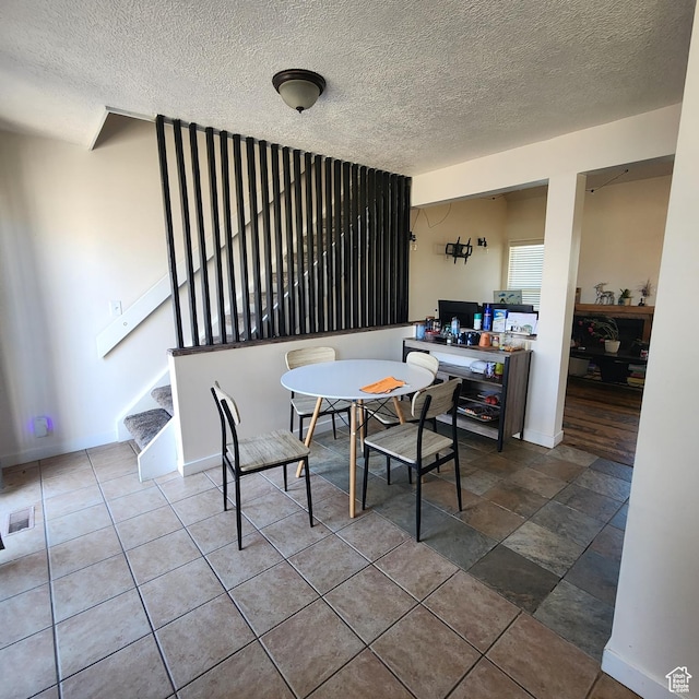 dining space with a textured ceiling, baseboards, stairs, and visible vents
