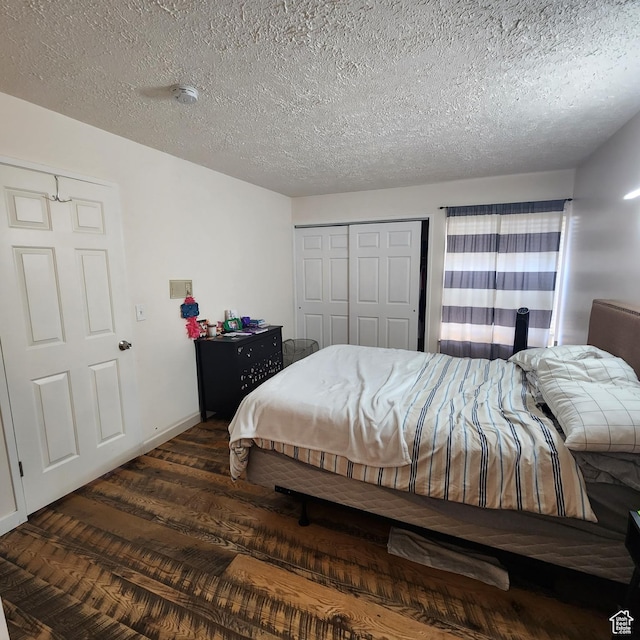 bedroom featuring baseboards, a closet, wood finished floors, and a textured ceiling