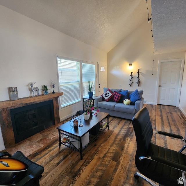 living room featuring a textured ceiling, baseboards, a fireplace, lofted ceiling, and hardwood / wood-style floors