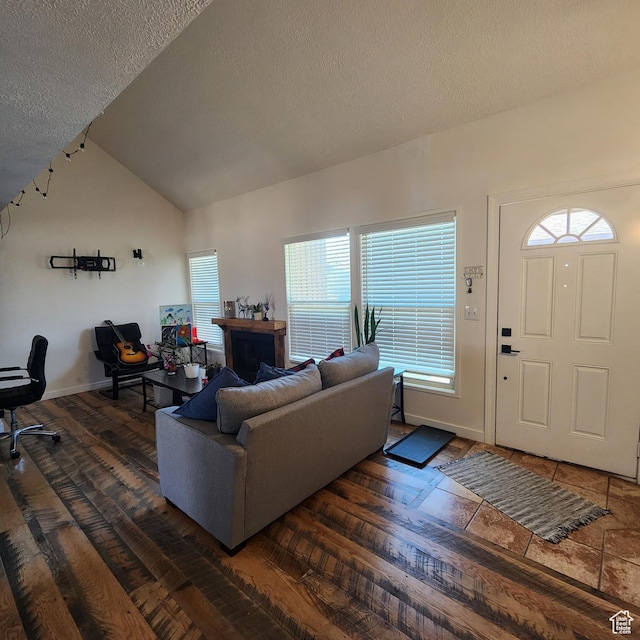 living room featuring dark wood-style floors, baseboards, vaulted ceiling, and a textured ceiling
