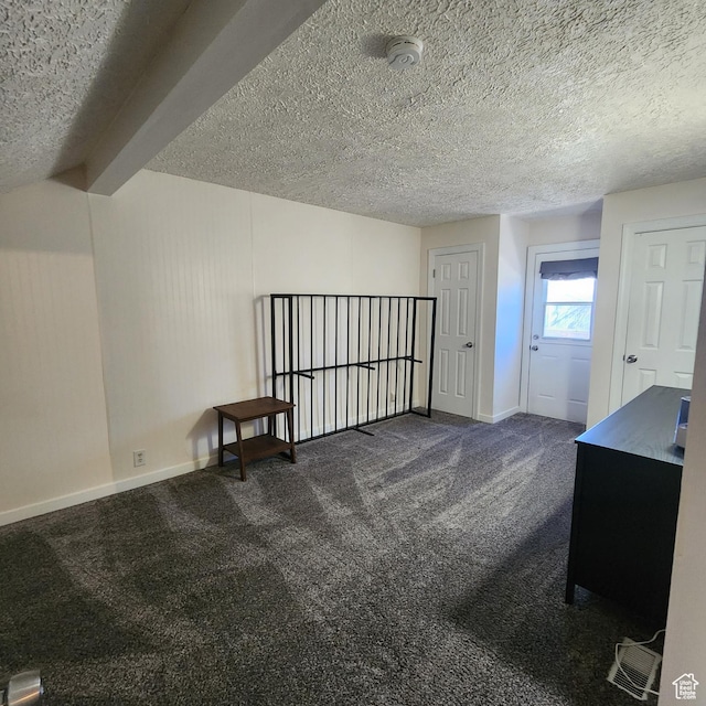 additional living space with baseboards, a textured ceiling, and dark carpet