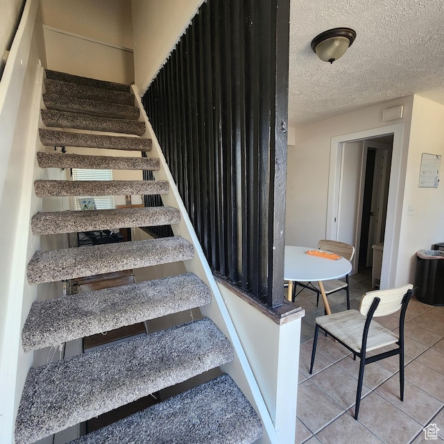 stairway featuring tile patterned flooring and a textured ceiling