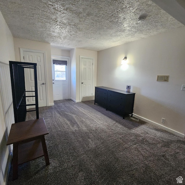 interior space featuring baseboards, a textured ceiling, and carpet