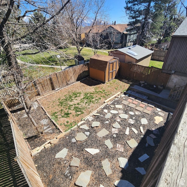 view of yard with a storage unit, a fenced backyard, and an outbuilding
