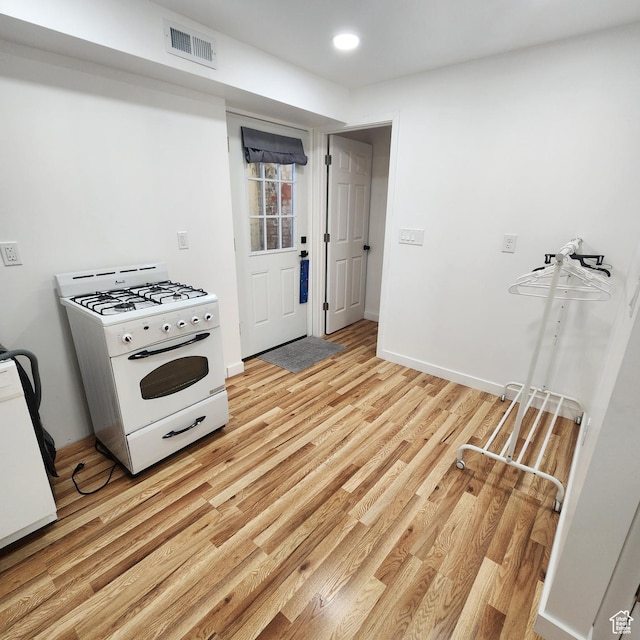 kitchen featuring white gas stove, baseboards, light wood-style floors, and visible vents