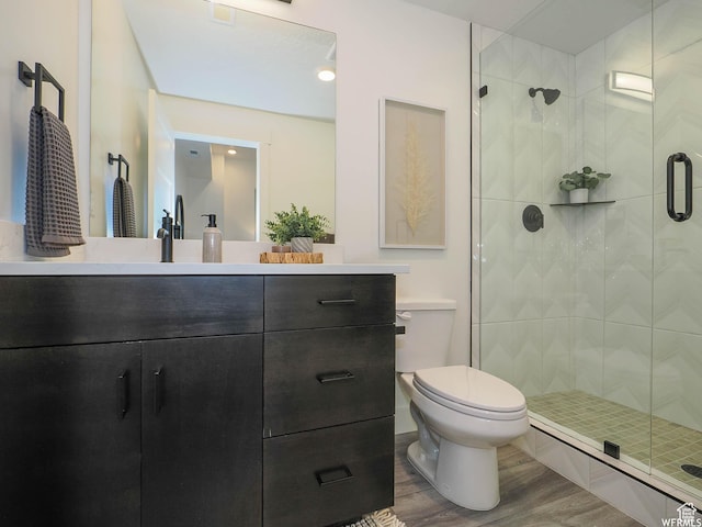 full bathroom with a shower stall, wood finished floors, toilet, and vanity