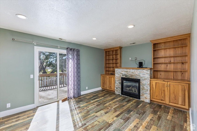 100 Crayon Ct, Logan, UT 84321 - unfurnished living room with a textured ceiling, a stone fireplace, baseboards, recessed lighting, and dark wood-type flooring