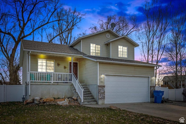 traditional home with covered porch, driveway, a garage, and fence
