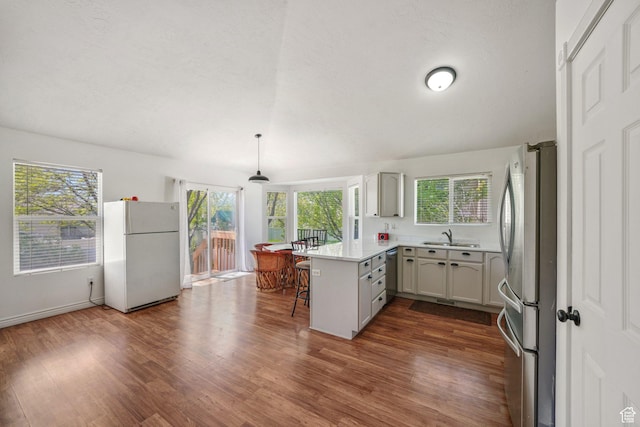3429 W Picabo St S, Taylorsville, UT 84129 - kitchen featuring appliances with stainless steel finishes, a peninsula, a sink, dark wood-style flooring, and plenty of natural light