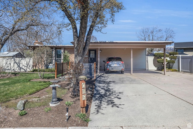 ranch-style house with an attached carport, fence, and concrete driveway