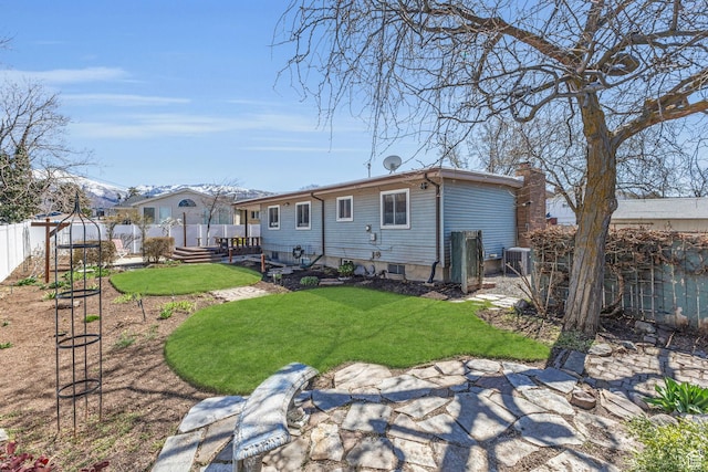 back of house featuring cooling unit, a chimney, a fenced backyard, and a yard
