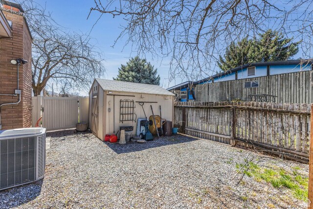 view of yard featuring central air condition unit, a fenced backyard, a storage unit, and an outbuilding