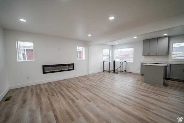 627 W La Salle Dr, Murray, UT 84123 - unfurnished living room featuring baseboards, light wood-style flooring, visible vents, and a wealth of natural light
