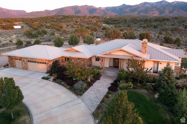 view of front of property with driveway, an attached garage, stone siding, and a mountain view