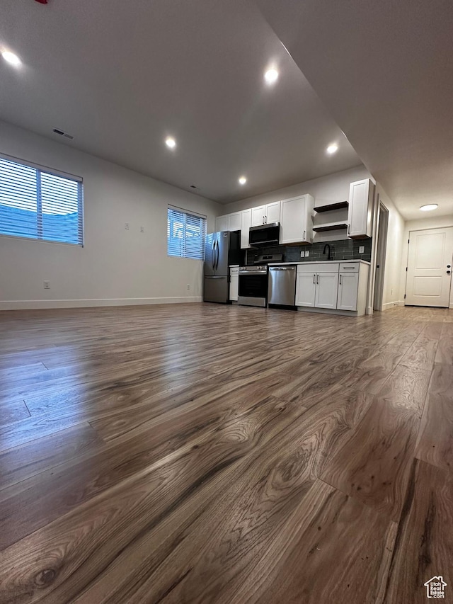kitchen featuring dark wood finished floors, stainless steel appliances, open floor plan, and white cabinetry