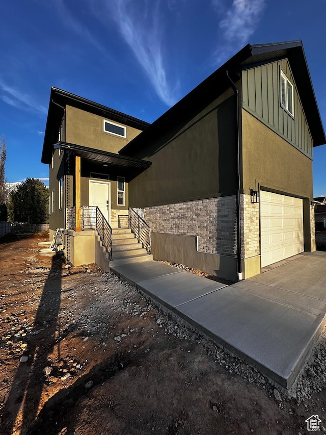 view of front facade with stucco siding, board and batten siding, and a garage