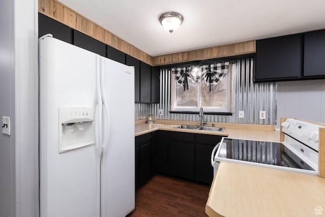kitchen with light countertops, a sink, dark cabinets, and white appliances