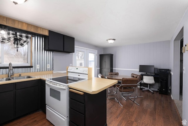 kitchen with light countertops, a sink, a peninsula, dark wood-style floors, and white range with electric stovetop