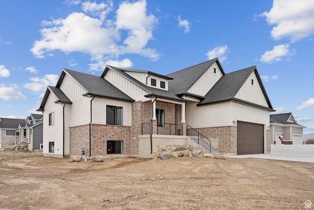 view of front of home with driveway, board and batten siding, brick siding, a shingled roof, and a garage