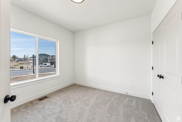 carpeted spare room featuring baseboards and visible vents