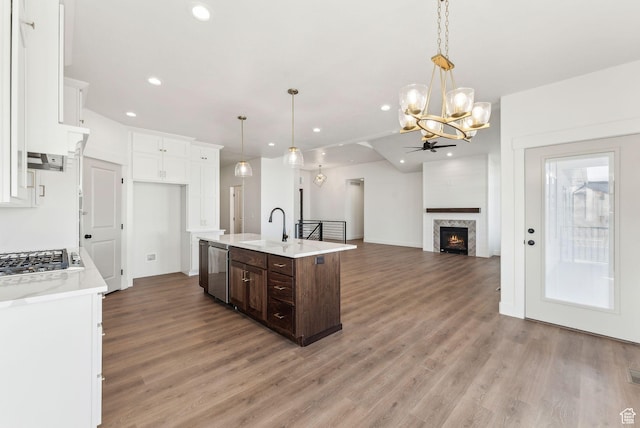 kitchen featuring white cabinets, light countertops, appliances with stainless steel finishes, dark brown cabinetry, and ceiling fan with notable chandelier