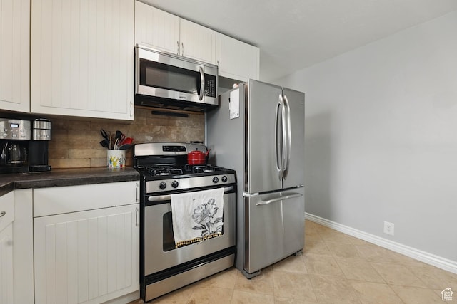 2645 S Masonic Cir E, South Salt Lake, UT 84115 - kitchen with baseboards, decorative backsplash, dark countertops, white cabinets, and appliances with stainless steel finishes