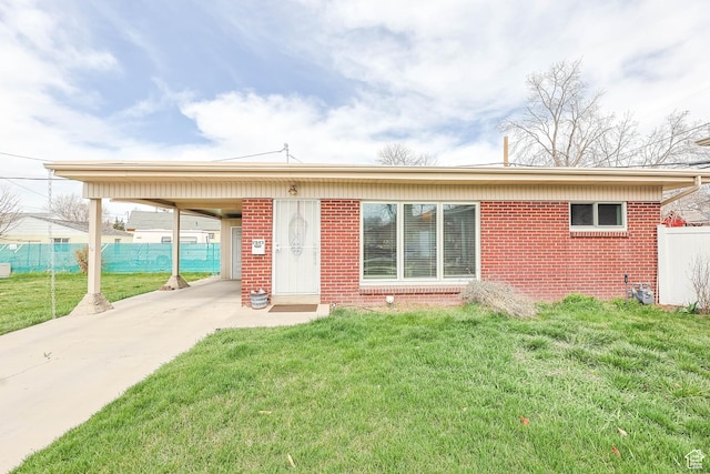 rear view of property featuring brick siding, a yard, and a carport