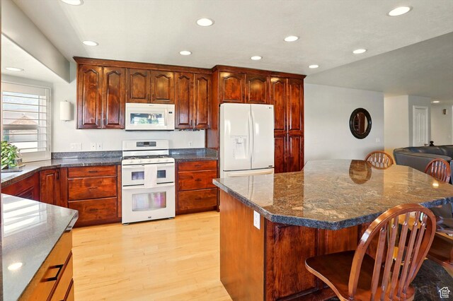 3011 N 1000 W, Pleasant View, UT 84414 - kitchen with white appliances, a kitchen breakfast bar, light wood finished floors, recessed lighting, and dark stone countertops