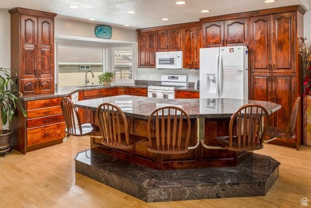 3011 N 1000 W, Pleasant View, UT 84414 - kitchen with a kitchen breakfast bar, white appliances, dark stone countertops, a sink, and light wood-style flooring