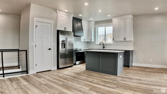 kitchen featuring light wood-style floors, light countertops, stainless steel appliances, decorative backsplash, and baseboards