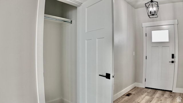 entrance foyer featuring baseboards, light wood-type flooring, and an inviting chandelier