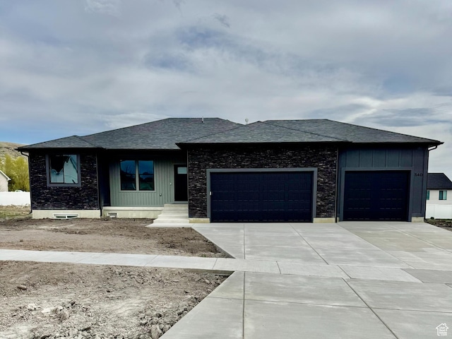 prairie-style home featuring roof with shingles, driveway, board and batten siding, and an attached garage
