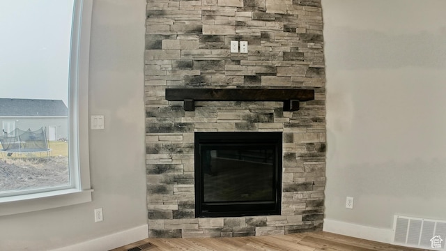 room details with visible vents, baseboards, wood finished floors, and a fireplace