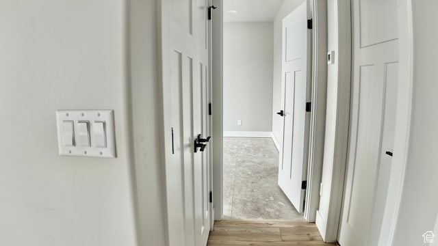 corridor with baseboards and wood finished floors