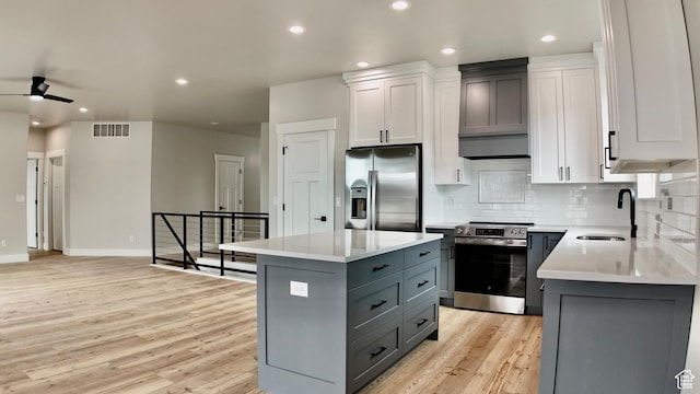 kitchen featuring light wood-type flooring, light countertops, gray cabinetry, stainless steel appliances, and a sink
