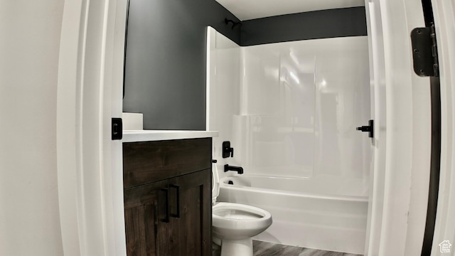 bathroom featuring toilet, wood finished floors, vanity, and shower / bathtub combination