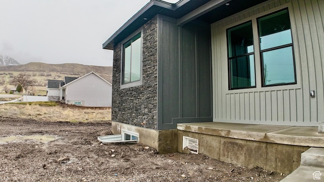 view of side of home featuring a mountain view, board and batten siding, and stone siding