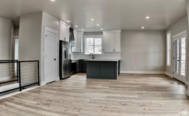 kitchen with light wood-style flooring, recessed lighting, stainless steel refrigerator with ice dispenser, a sink, and baseboards