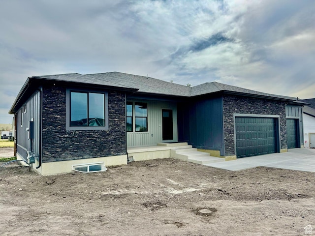 prairie-style home featuring an attached garage, driveway, and stone siding