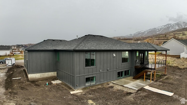 rear view of property with board and batten siding, a mountain view, and a shingled roof