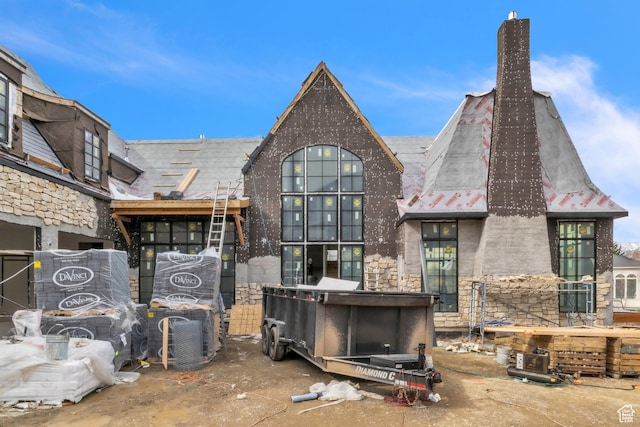 rear view of property featuring stone siding and a chimney