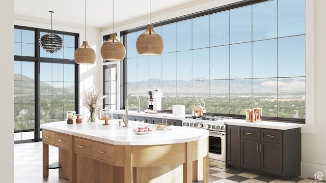 kitchen with light countertops, high end stainless steel range oven, pendant lighting, and light floors