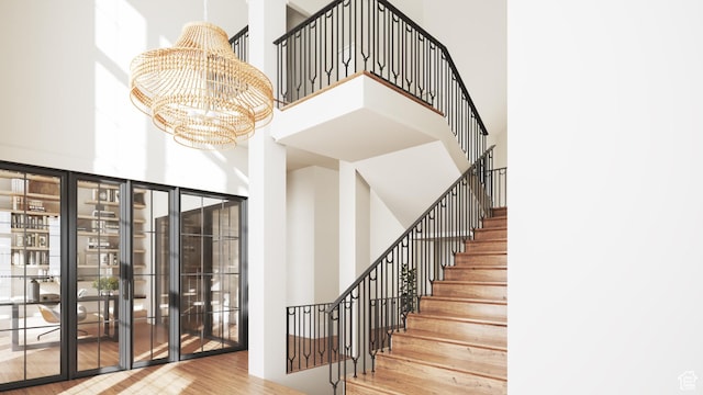 staircase featuring a high ceiling, a chandelier, and wood finished floors