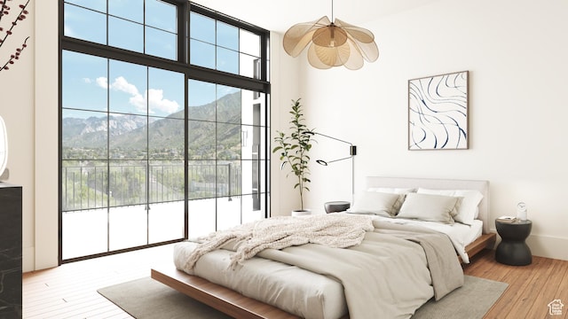 bedroom with a wall of windows, access to exterior, a mountain view, and wood-type flooring