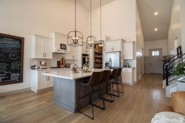 1438 N Jerry Gertsch Ln, Midway, UT 84049 - kitchen featuring light countertops, a kitchen bar, light wood finished floors, white cabinets, and appliances with stainless steel finishes