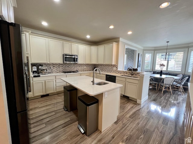 kitchen with stainless steel microwave, decorative backsplash, a sink, and gas cooktop