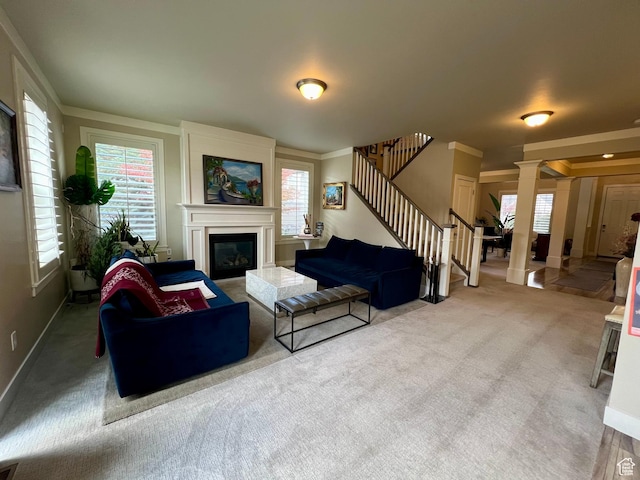 living room featuring stairs, crown molding, carpet flooring, a glass covered fireplace, and a healthy amount of sunlight