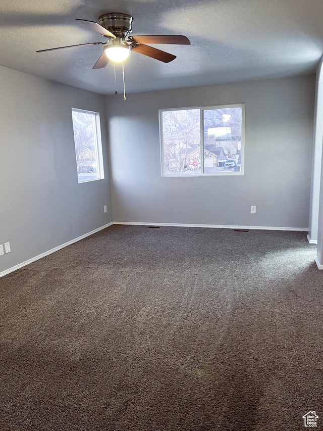 5498 Scarsborough Way, Stansbury Park, UT 84074 - spare room featuring dark carpet, a ceiling fan, baseboards, and a textured ceiling